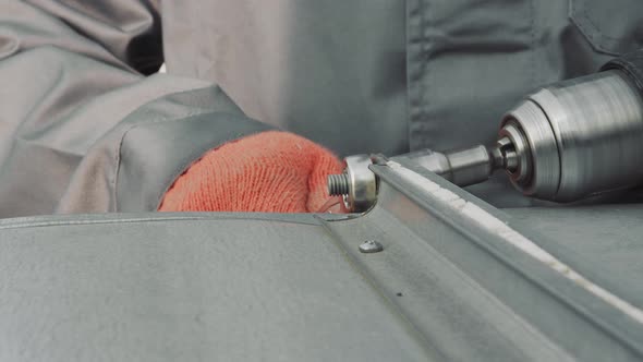 Closeup Worker Locksmith Tightens Nut with Screwdriver Closeup. The Master Tightens a Nut Metal