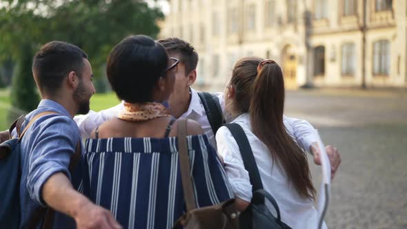 Joyful Caucasian Young Man Running in Slow Motion to Group of Multiethnic Friends Hugging Kissing