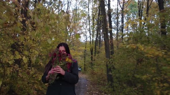 Girl with Flowers Walks in the Autumn Forest