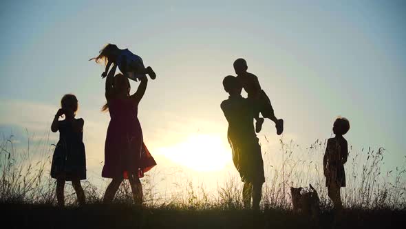 Happy Parents Circle Their Children Against the Sunset.