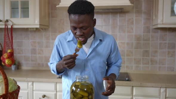 Portrait of Young Man Tasting Canned Cucumber with Satisfied Facial Expression