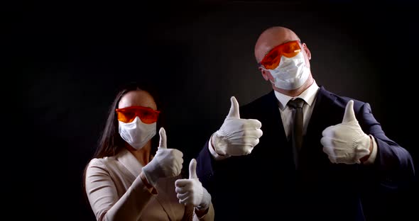 Portrait of a Couple in Business Clothes on a Black Background. They Wear Disposable Masks and