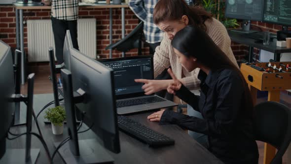 Two Software Engineers Analyzing Source Code Running on Laptop Screen Looking for Errors