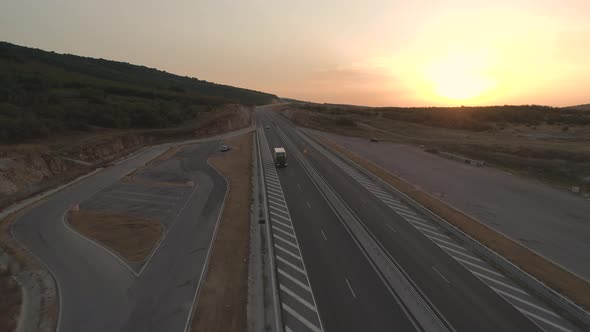 Drone Follows Semi Truck on a New Condition Highway Under Dramatic Sunset Sky