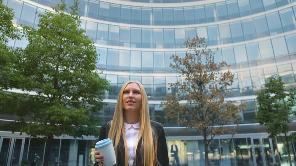 Stylish Business Woman with Coffee on Street. From Below of Serious Blond Executive Young Woman in