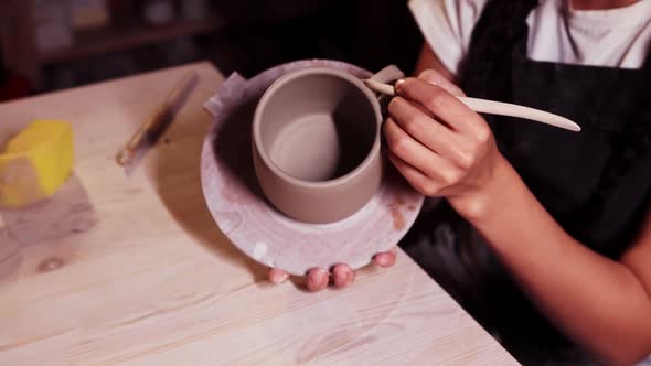 Pottery in the Studio Asian Woman Holding a Cup on the Plate and Smearing Clay on the Joint on the