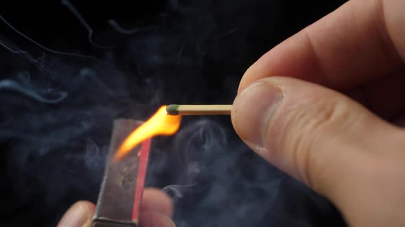 The match moves on the side of the matchbox and light the fire.
