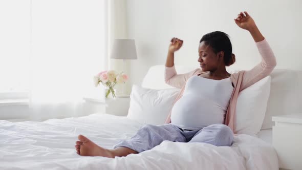 Happy Pregnant African Woman Stretching in Bed 