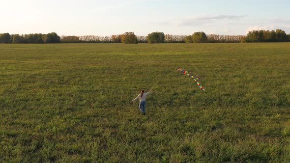 The Girl Runs with a Kite on a Green Field