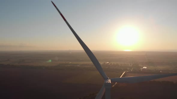 Aerial wind power turbine rotor blades backlight by sunset beam rays, Renewable energy source