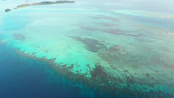 Aerial: flying over coral reef tropical caribbean sea, turquoise blue water. Ind