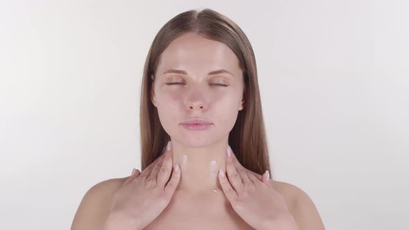 Beautiful Woman Applying Lotion to Neck and Collarbone