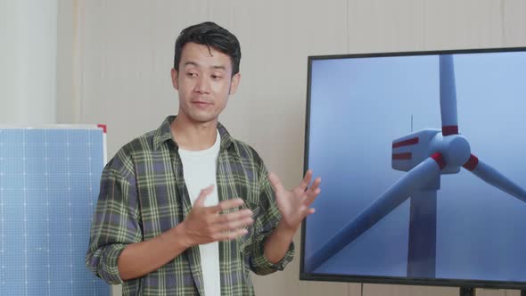 Asian Man Engineer With Solar Cell Presenting About The Wind Turbine At The Office