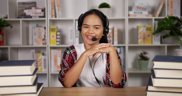 Happy female student in headphones and glasses talking at camera