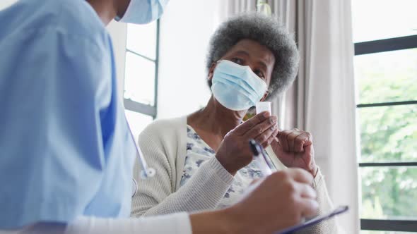 African american female doctor and senior female patient in face masks