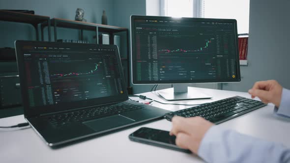 Close Up of Trader Monitoring Stock Market on Two Computers