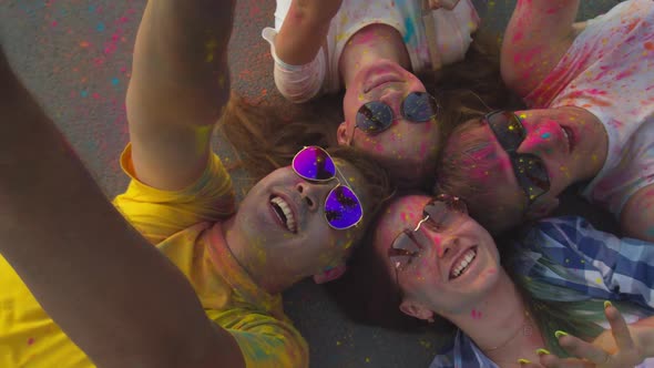 A Group of Friends at the Festival of Colors Holi is Lying on the Asphalt in Soiled Clothes and