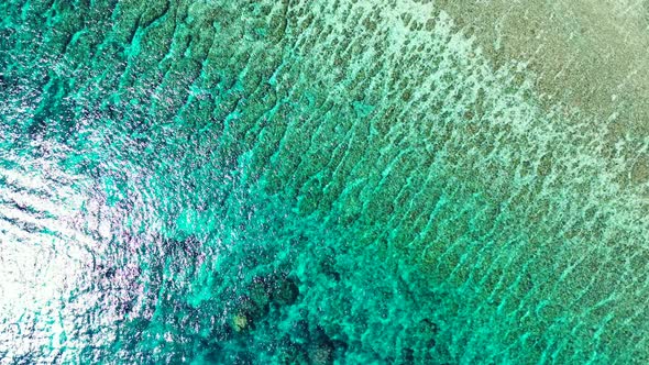 Wide birds eye tourism shot of a white paradise beach and aqua turquoise water background in 4K