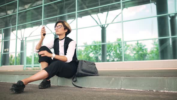 Young Beautiful Businesswoman Sitting on Street Speaking on Phone Business Centre Background