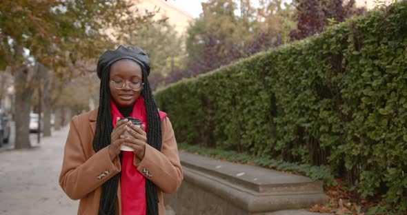 Young Black Woman Warms Her Hands with a Cup of Coffee