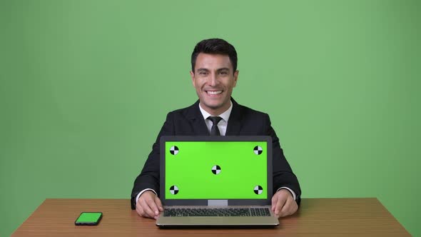 Young Handsome Hispanic Businessman Against Green Background