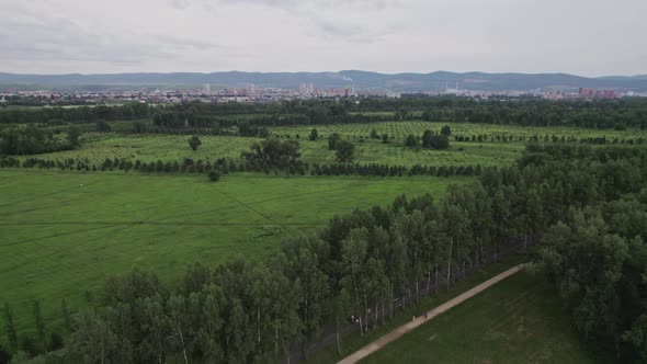 Drone Flight Green Park City and Mountains in the Background