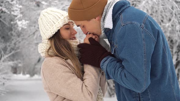 A man warms his hands to a woman in a winter park. Family theme. Valentine's day