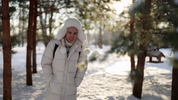 Joyful Young Man is Strolling Alone in Park and Playing with Pine Branches in Winter