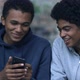 Black male teenager showing friend photos on smartphone - VideoHive Item for Sale
