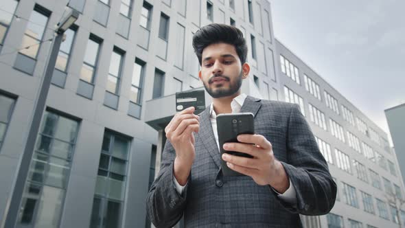 Stylish Bearded Man Doing Online Purchases While Standing Near Office Building