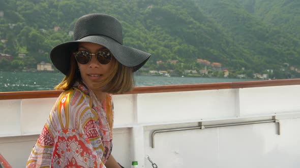 A woman wears a hat while traveling to luxury resort town on a ferry near Lake Como, Italy, Europe