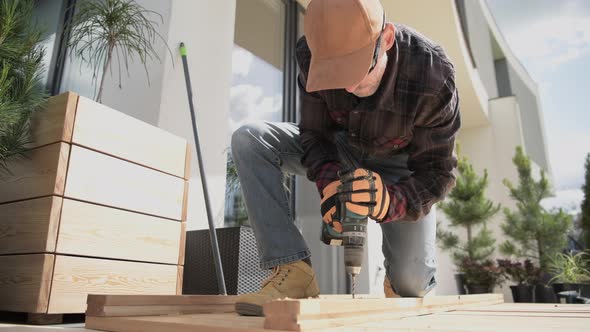 Carpenter Building Wooden Deck In Garden.  alt