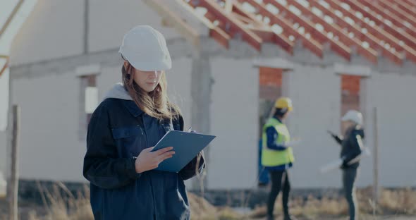Confident Young Female Contractor Writing on Clipboard