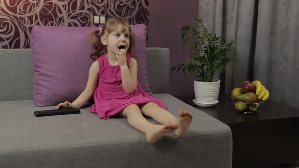 Little Child Sitting on Couch While Watching TV. Kid Girl Watch Television