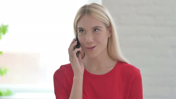 Young Blonde Woman Talking on Phone, Discussing Work