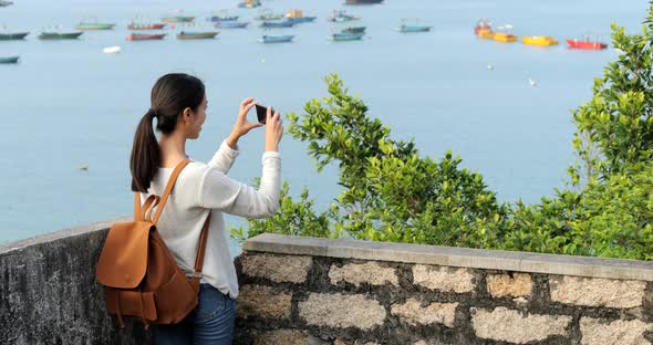 Woman go hiking and taking photo of the sea view