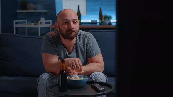 Scared Man Watching Horror Film on TV Eating Popcorn Sitting on Sofa