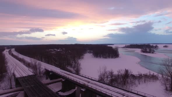 Aerial flying shot of beautiful winter sunset over railroads in coastal rural area