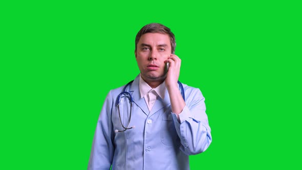 Young Doctor Talking to a Smartphone on Green Chroma Key Background