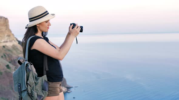 Attractive Young Woman Photographer in Hat Taking Photo or Video Using Professional Camera