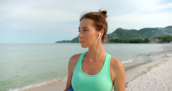 Sport Woman Walks on the Beach and Listening the Music Swop the Songs By Doubleclick on Headphones
