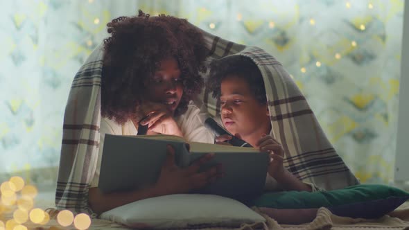 African American Mother and Kid Reading Book before Bedtime