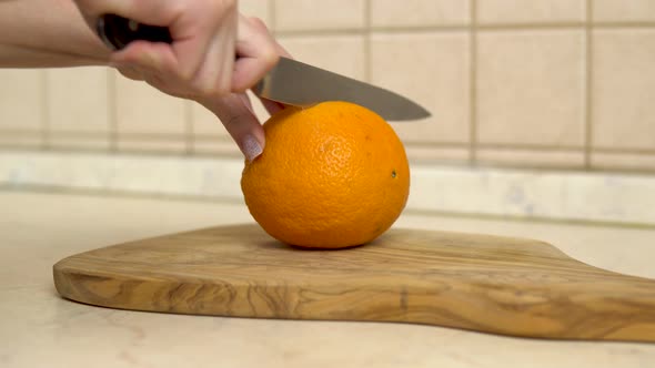 Woman Cuts an Orange in Half. Woman's Hand Close Up