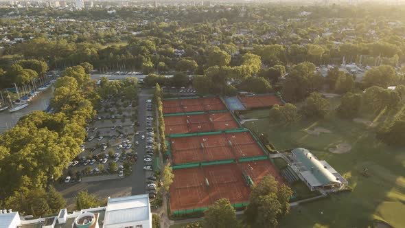 Aerial cinematic shot of a private sport club with tennis courts, a golf field and a parking lot at