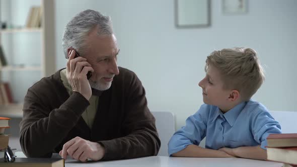 Senior Man Talking on Phone, Grandson Nodding Happily, Family Communication