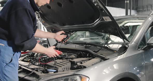 Car Mechanic Checking Power Voltage Of Car Battery In The Workshop
