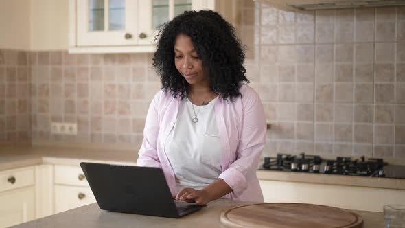 Portrait of Concentrated Intelligent African American Young Woman Typing on Laptop Keyboard Thinking