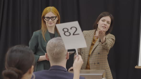Two Professional Female Auctioneers Calling Out Bids
