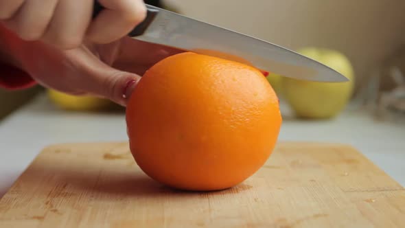 Woman Slicing Orange on Wooden Board. To Make Fresh Smoothie