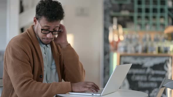 African Man Having Neck Pain While Using Laptop in Cafe